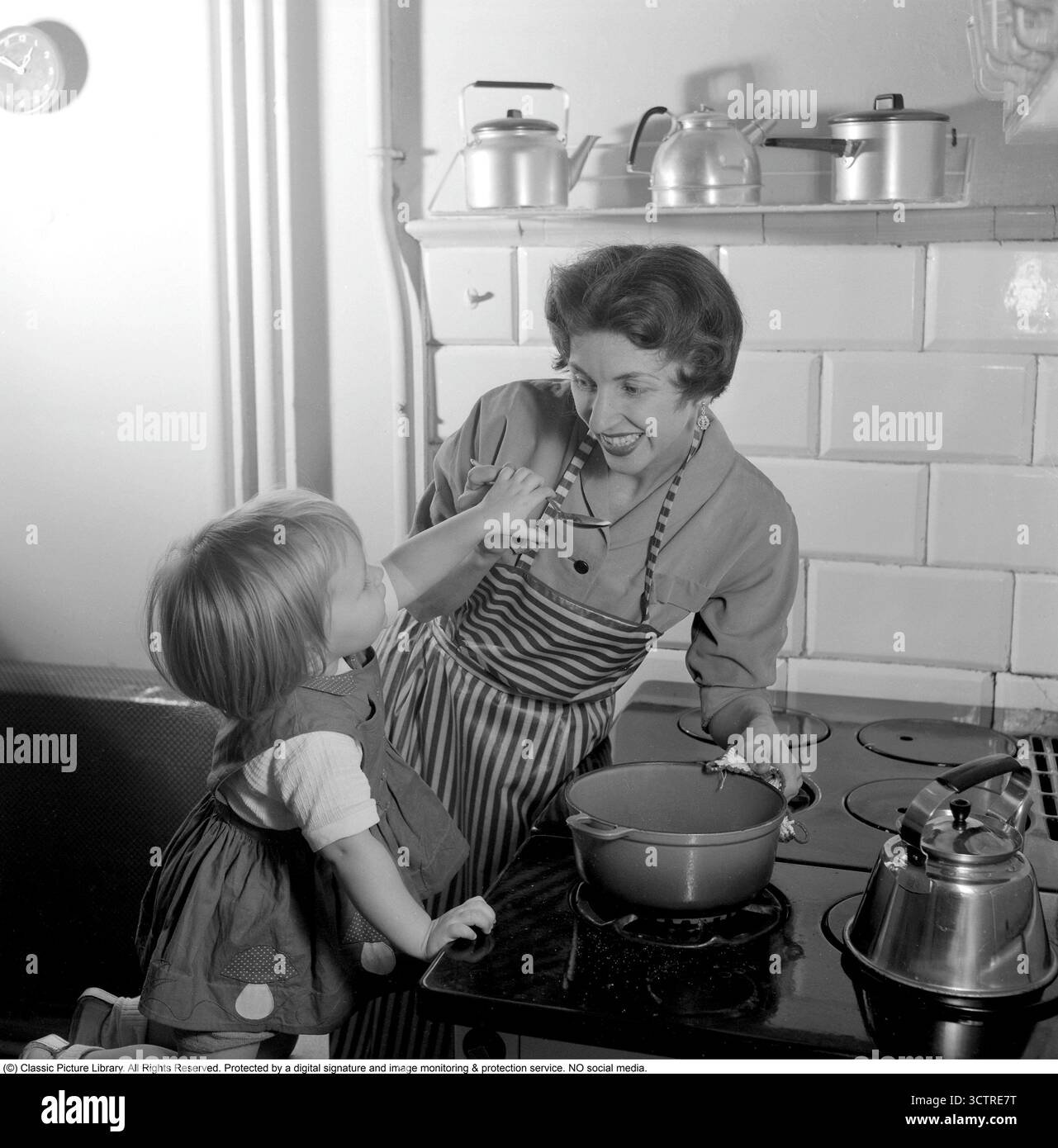 Nel 1956, una madre e una figlia stanno al piano cottura a gas, preparando la cena insieme. Su uno scaffale dietro di loro si trova la classica "Visseljohanna", la caffettiera fischiante. (Rif. Conard 3159) Foto Stock