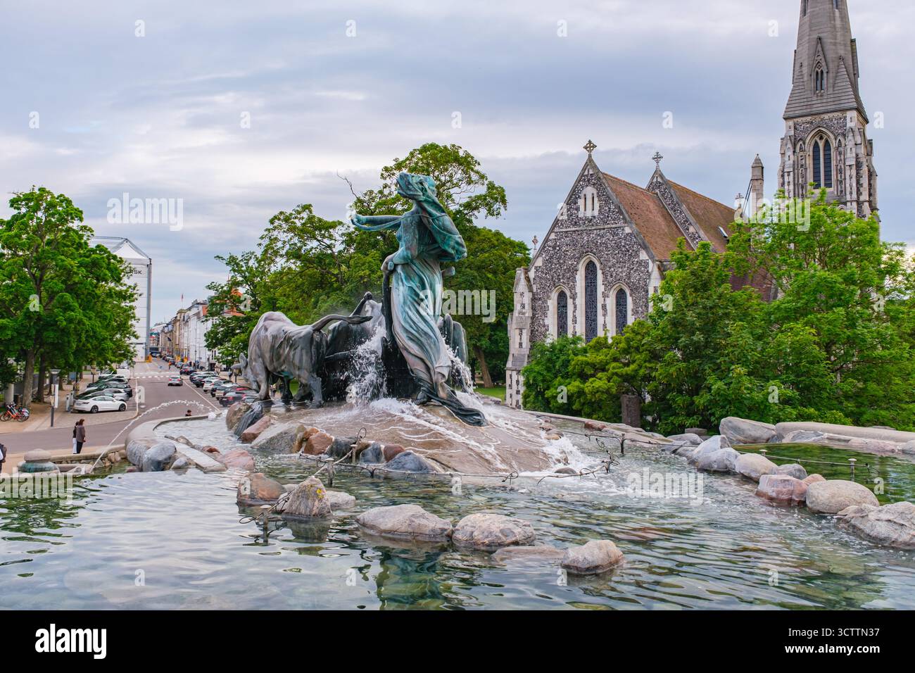 Vista della fontana Gefion e della chiesa di Sant'Alban sullo sfondo, circondata da alberi verdi Foto Stock