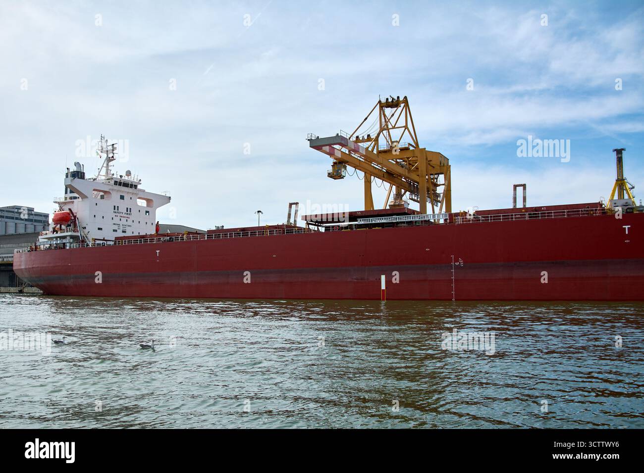 Venezia. Italia - 8 ottobre 2025: Una nave portarinfuse viene scaricata da una gru speciale presso il porto industriale di Venezia. Foto Stock