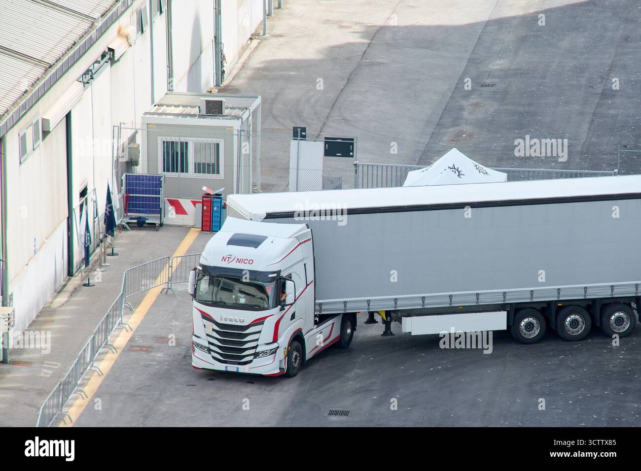 Venezia. Italia - 8 ottobre 2025: Un autocarro Iveco S-Way con rimorchio, gestito da NT Nico, è parcheggiato in un cantiere industriale a Venezia. Foto Stock