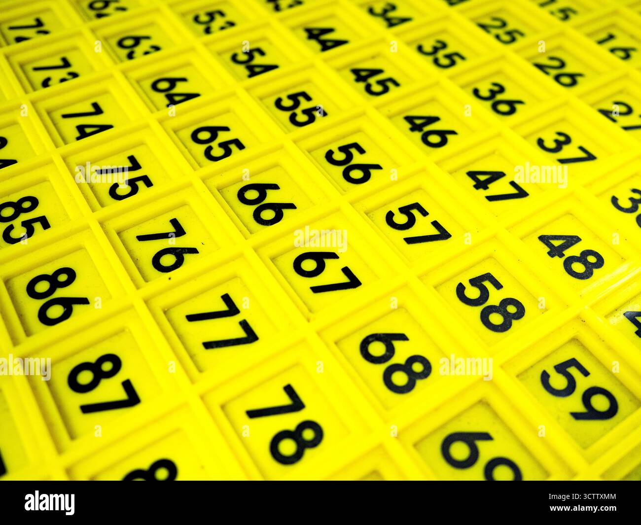 Immagine ravvicinata di una griglia numerica gialla con numeri neri in singoli quadrati di plastica. Comunemente utilizzato come ausilio per l'apprendimento matematico per la preimpostazione Foto Stock