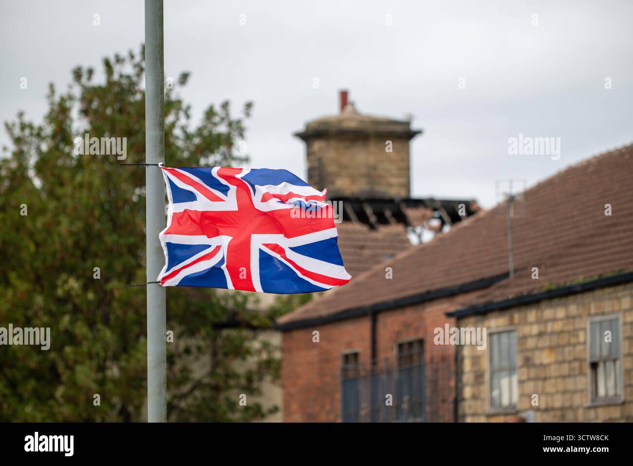 Bandiera Union Jack che sventola su un palo di fronte agli edifici britannici, simbolo del Regno Unito Foto Stock