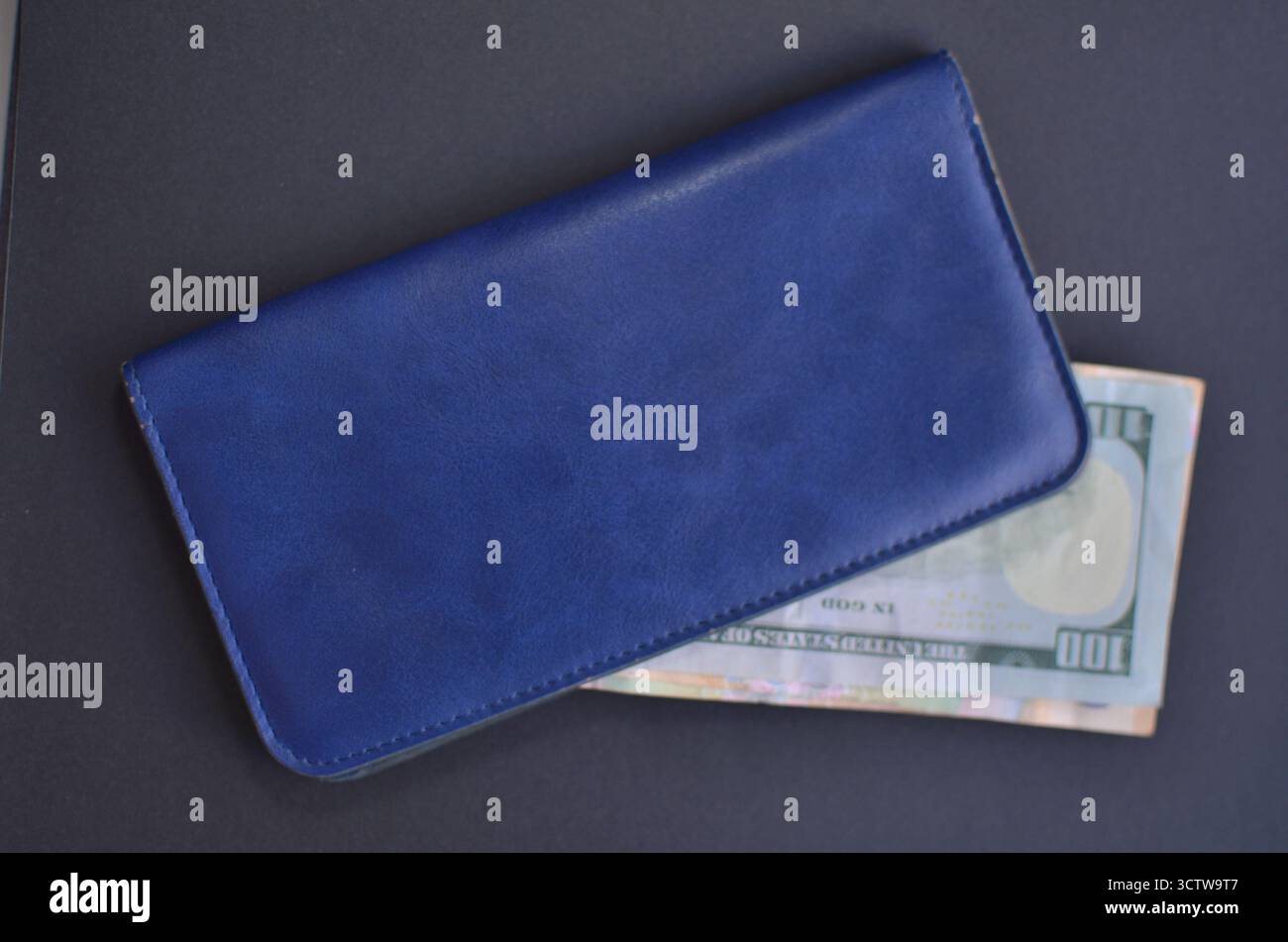 Una borsa blu in pelle con una banconota da cento dollari Foto Stock