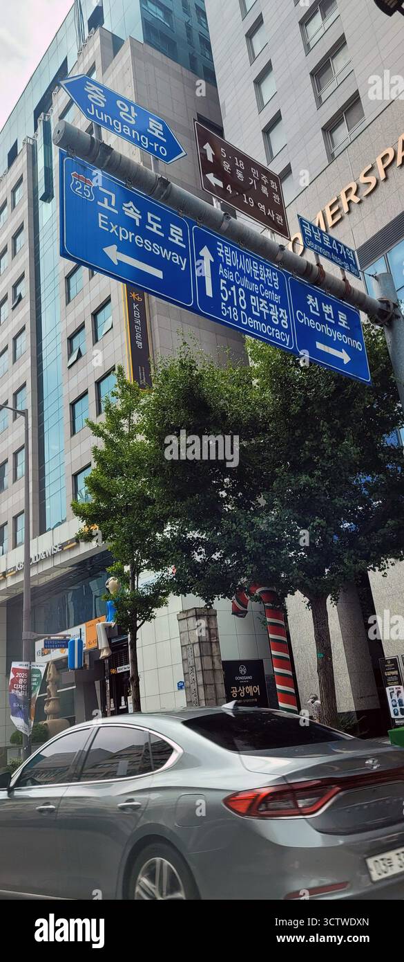 Una fotografia di una scena di strada a Gwangju, la sesta metropoli più grande della Corea del Sud, con numerosi cartelli direzionali che puntano verso luoghi di interesse come l'Asia Culture Center e la storica Piazza della democrazia 5?18. Il movimento per la democrazia 5,18 fu una rivolta fondamentale a favore della democrazia a Gwangju nel maggio 1980, e la rivoluzione 4:19, una protesta guidata da studenti nell'aprile 1960 che portò alle dimissioni del presidente Syngman Rhee, entrambi eventi profondamente significativi nella lotta della Corea del Sud contro il governo autoritario. 2025. Foto Stock