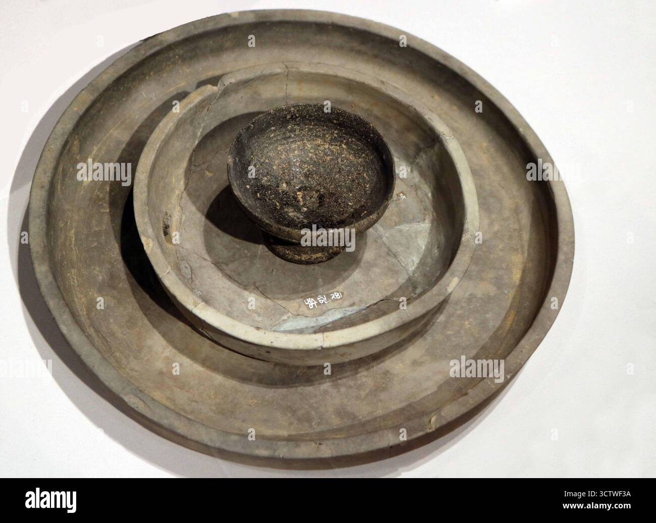 Una fotografia di tre piatti in terracotta con una ciotola centrale, esposta in una disposizione annidata, dall'era Silla, Corea. Questi pezzi fanno parte della collezione del Museo Nazionale di Gyeongju. Il regno di Silla (??, Silla, 57 a.C. ? 935 d.C.) fu uno dei tre regni di Corea, conquistando gli altri due per unificare la maggior parte della penisola coreana nel 668 d.C. c. 450 CE. Foto Stock