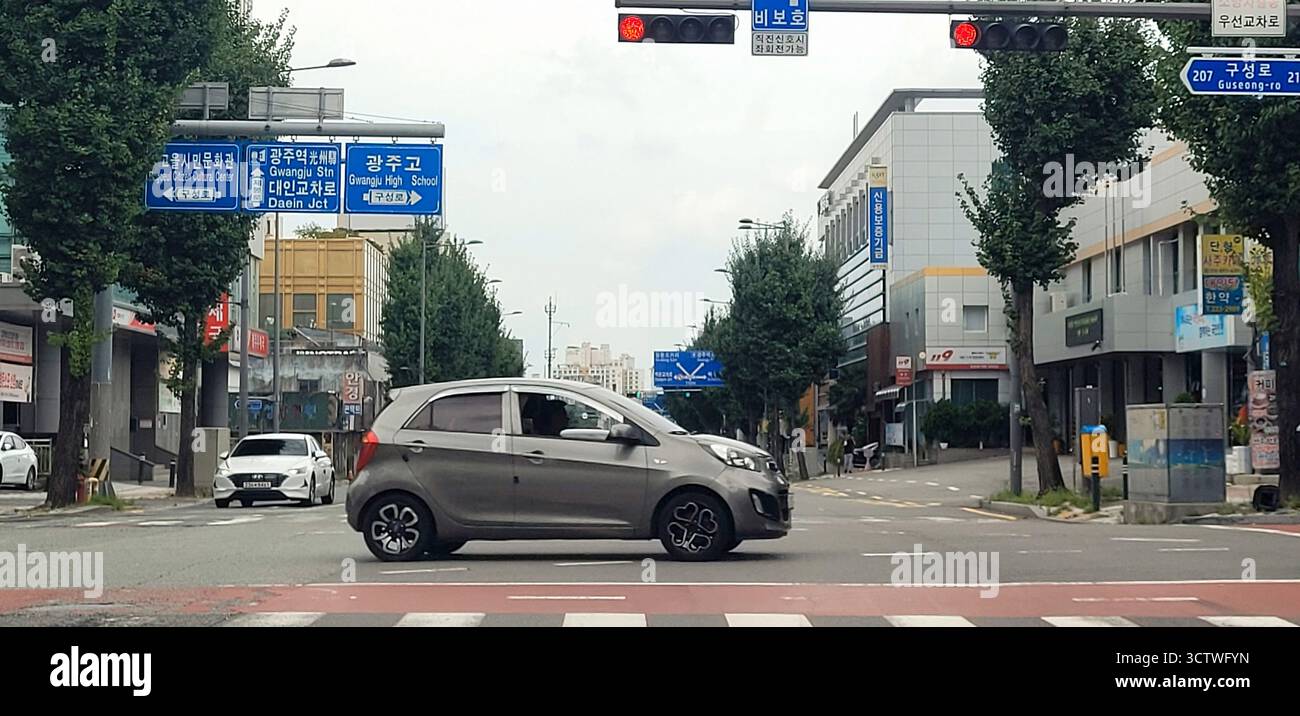 Una fotografia di una tipica scena di strada a Gwangju, la sesta metropoli più grande della Corea del Sud, con un Kia Morning grigio (Picanto) che gira ad un incrocio. Gwangju, una delle principali città della Corea del Sud, è nota per la sua ricca arte e cultura, e storicamente ha svolto un ruolo fondamentale nella lotta per la democrazia del paese durante la rivolta di Gwangju del 1980. 2025. Foto Stock