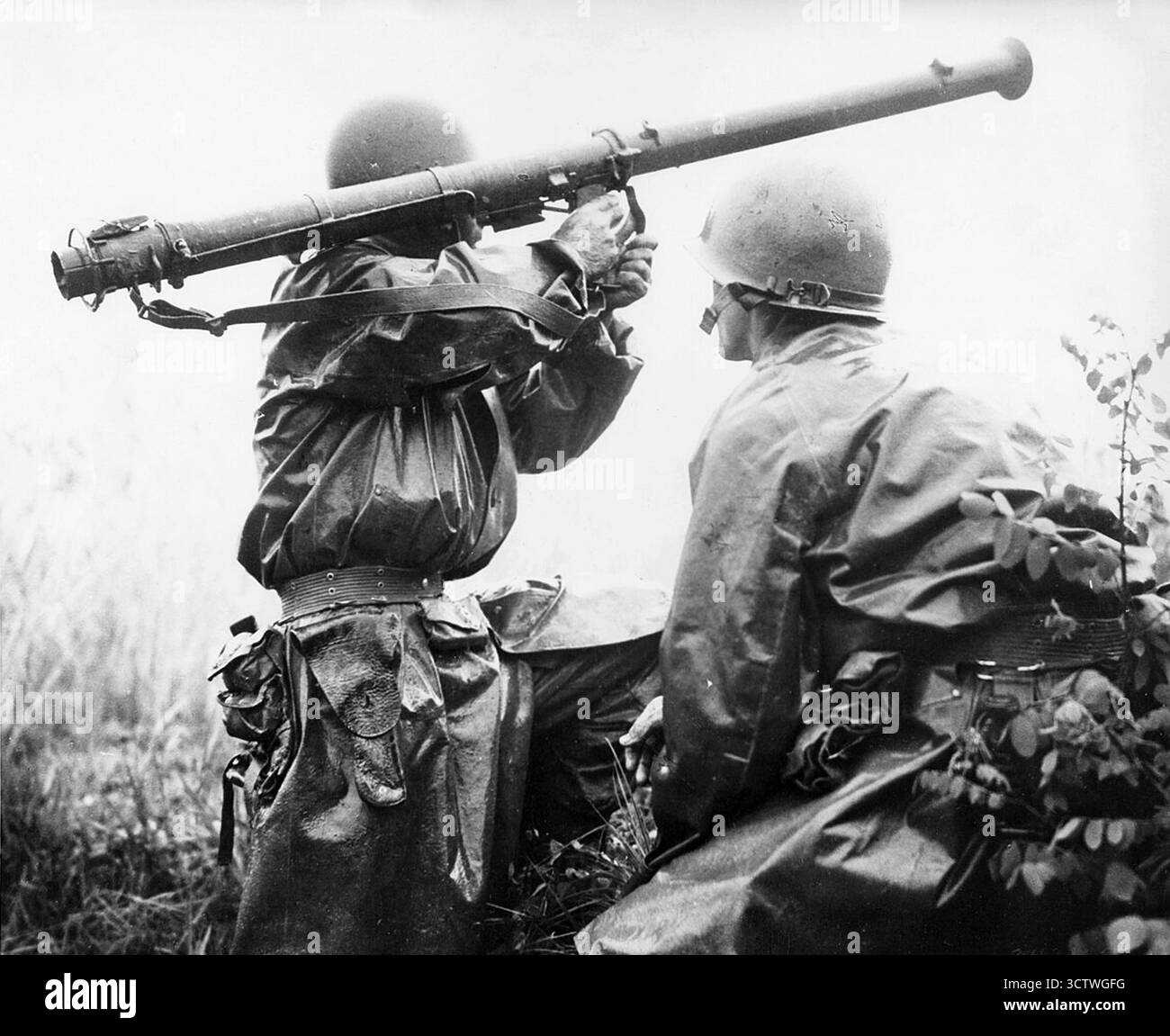 Una fotografia che cattura due soldati americani durante la battaglia di Osan, il primo scontro tra Stati Uniti e Corea del Nord durante la guerra di Corea, il 5 luglio 1950. Il soldato in primo piano, indossando un casco e un poncho o un'elegante pioggia, tiene un bazooka M9A1 sulla spalla. Alla Task Force Smith, una task force americana di 540 fanti supportata da una batteria di artiglieria, fu ordinato di combattere come retroguardia per ritardare l'avanzata delle forze nordcoreane mentre altre truppe statunitensi arrivarono per formare una linea difensiva più forte a sud, evidenziando l'iniziale impreparazione degli americani Foto Stock