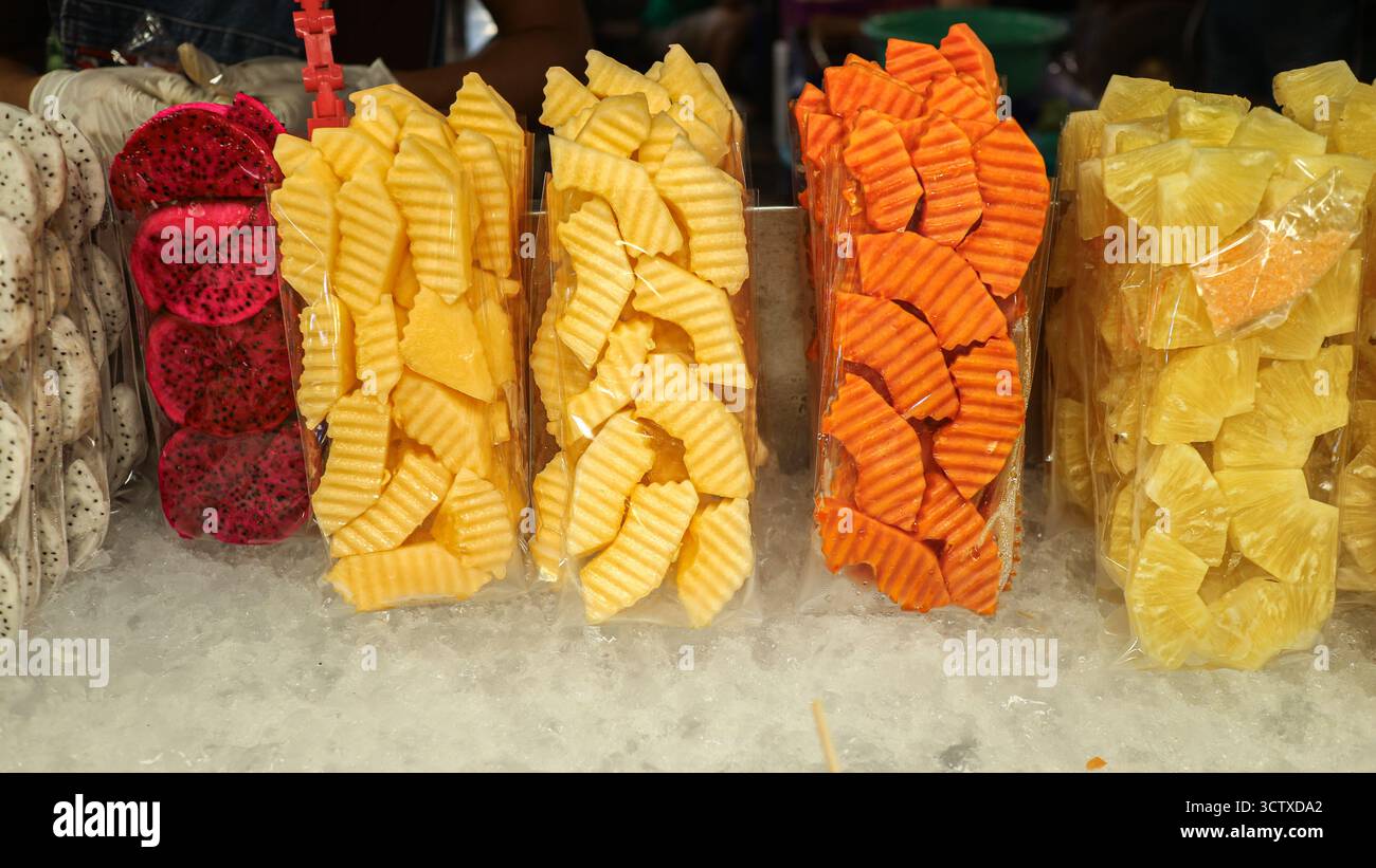 Frutta tropicale tagliata al momento (ananas, Drago, Papaya, melone tailandese) in sacchetti presso un fornitore di cibo di strada tailandese. Uno spuntino sano e pronto per il mercato. Foto Stock