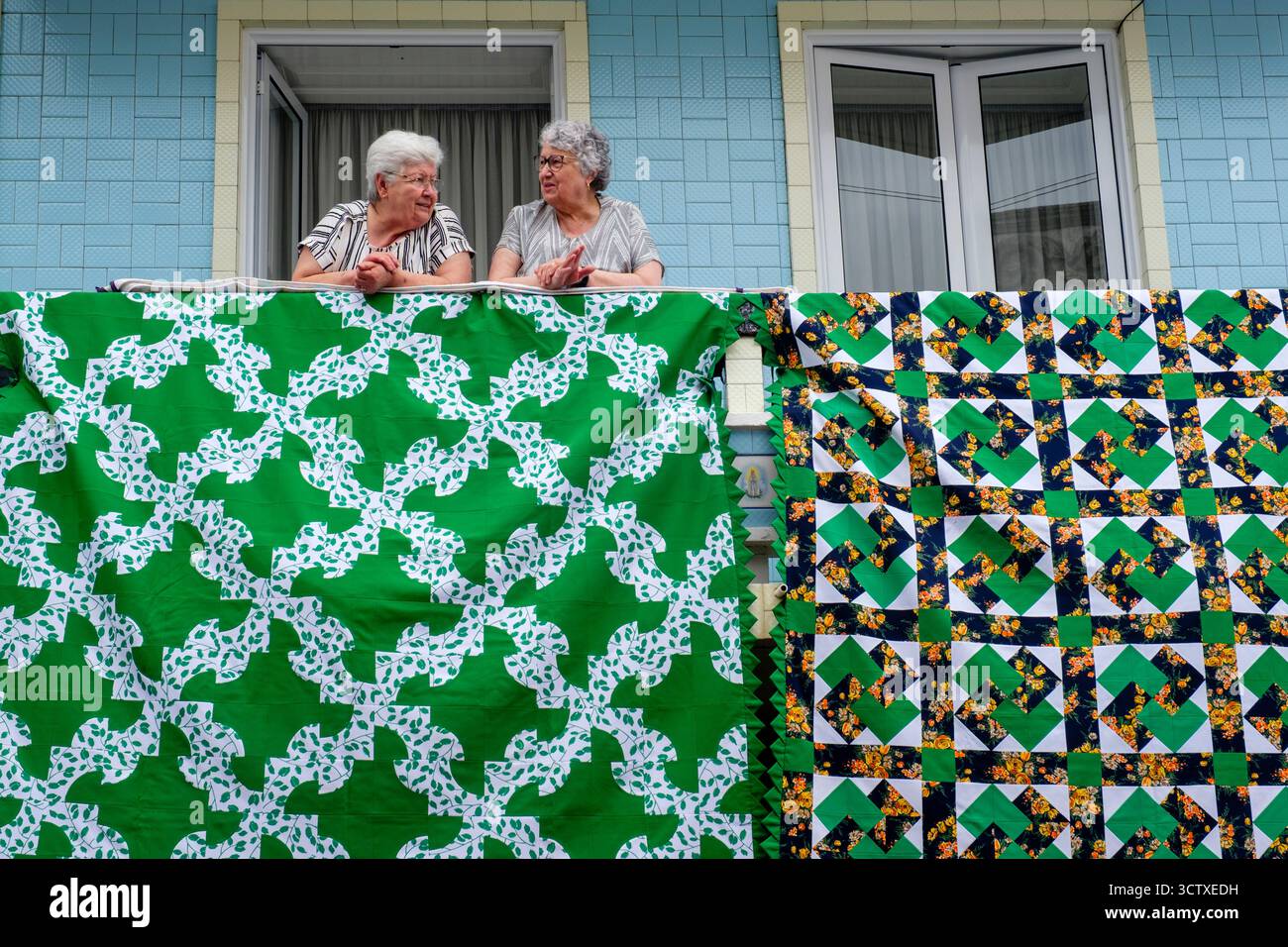 Vita da villaggio, due donne sul balcone decorate con trapunte per il Festival dello Spirito Santo, villaggio di Ribeirinha, isola di Terceira, Azzorre, Portogallo Foto Stock
