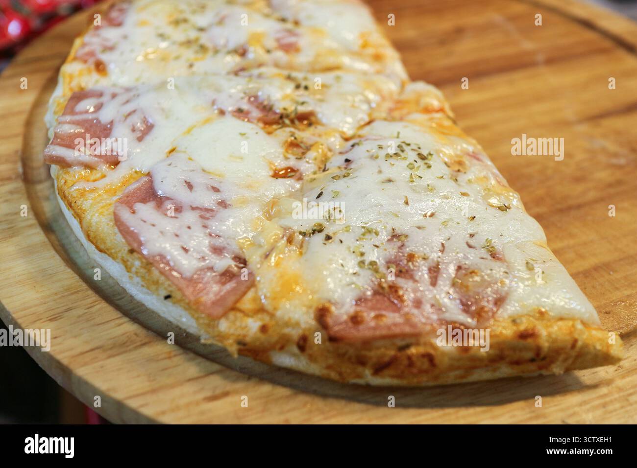 Primo piano di una mini Pizza a fette condita con salsiccia Bologna e formaggio fuso. Un popolare e veloce spuntino thailandese da strada. Foto Stock