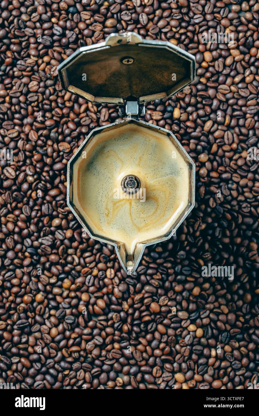 Vecchia macchina per il caffè geyser con bevanda appena preparata sullo sfondo dei chicchi di caffè tostati, primo piano, vista dall'alto, spazio per copiare. Concetti di COF Foto Stock
