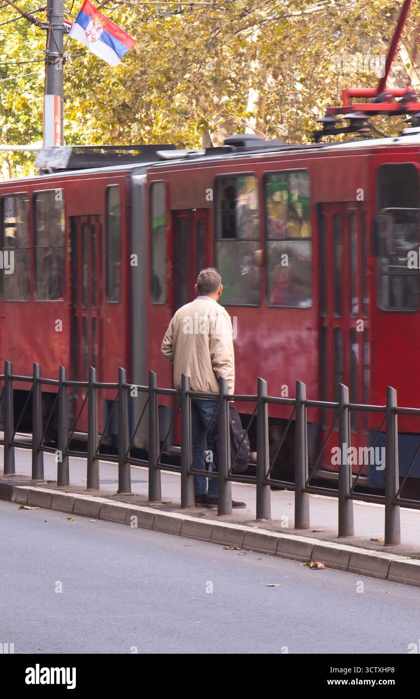 Belgrado, Serbia - 6 ottobre 2025: Un uomo da solo sulla fermata dell'autobus cittadino, in attesa di un trasporto pubblico, vista dall'angolo posteriore Foto Stock