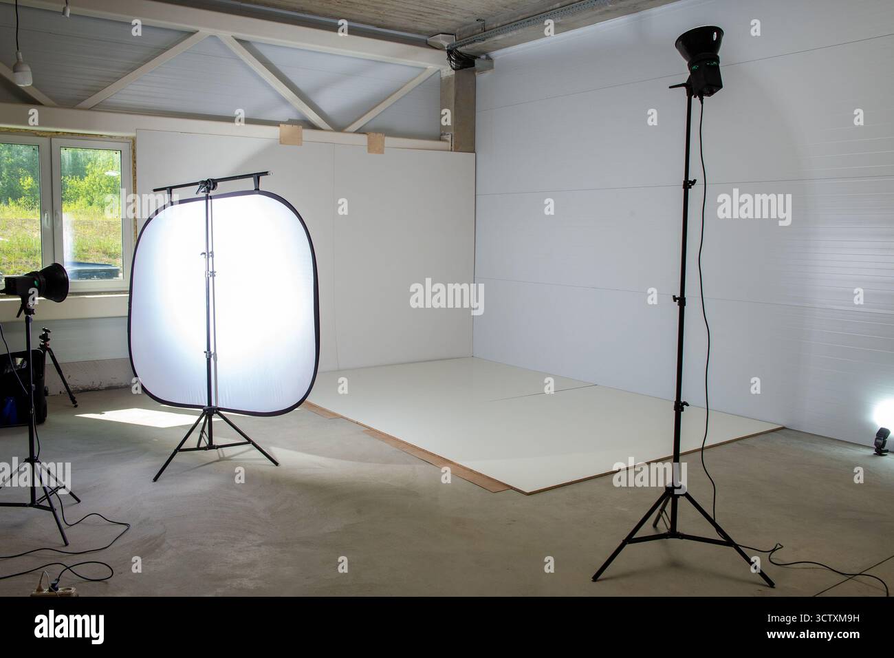 Area fotografica in un angolo della fabbrica per la fotografia dei prodotti, con stroboscopiche da studio e un ampio softbox che crea un'illuminazione soffusa e professionale. Foto Stock