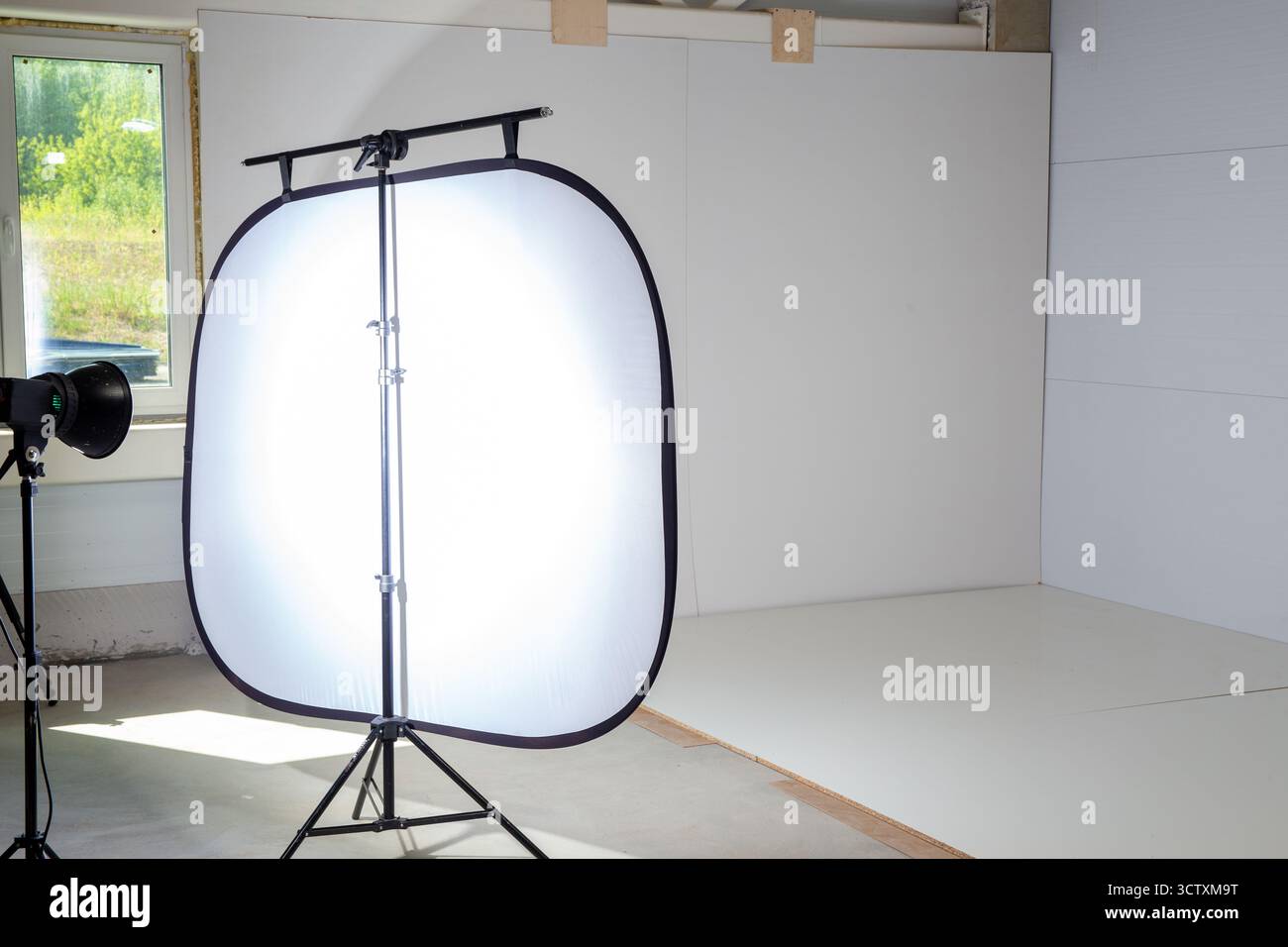 Area fotografica in un angolo della fabbrica per la fotografia dei prodotti, con stroboscopiche da studio e un ampio softbox che crea un'illuminazione soffusa e professionale. Foto Stock