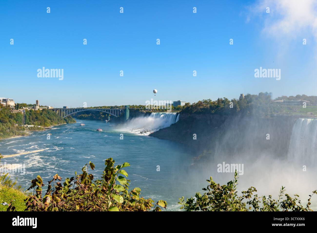 Una vibrante vista panoramica delle Cascate americane alle Cascate del Niagara, New York, con l'iconico Rainbow Bridge che collega gli Stati Uniti e il Canada nel Foto Stock