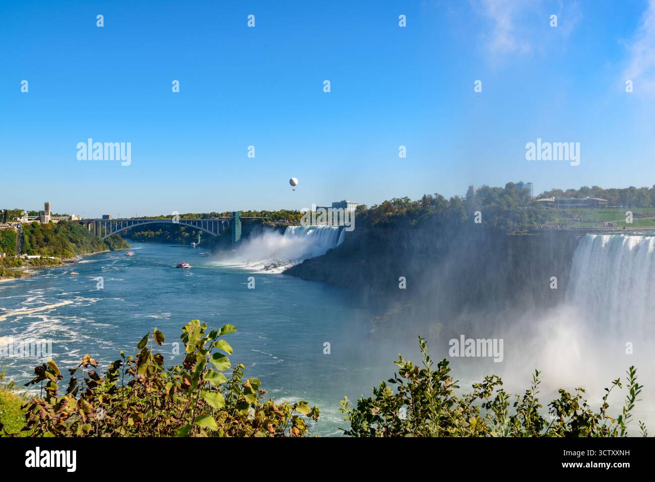 Una vibrante vista panoramica delle Cascate americane alle Cascate del Niagara, New York, con l'iconico Rainbow Bridge che collega gli Stati Uniti e il Canada nel Foto Stock