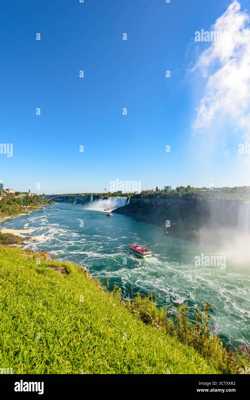 Una vibrante vista panoramica delle Cascate americane alle Cascate del Niagara, New York, con l'iconico Rainbow Bridge che collega gli Stati Uniti e il Canada nel Foto Stock