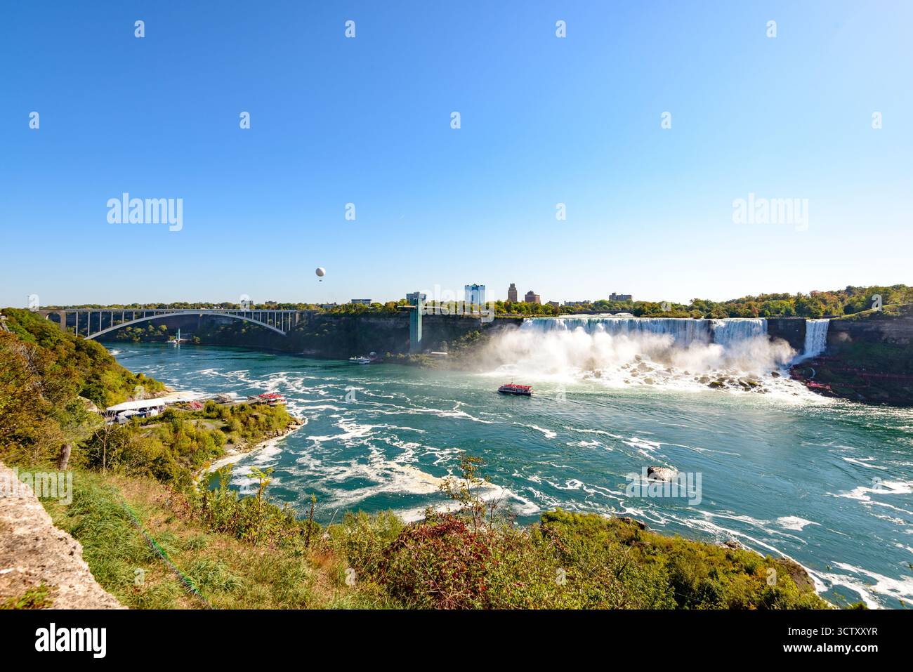 Una vibrante vista panoramica delle Cascate americane alle Cascate del Niagara, New York, con l'iconico Rainbow Bridge che collega gli Stati Uniti e il Canada nel Foto Stock