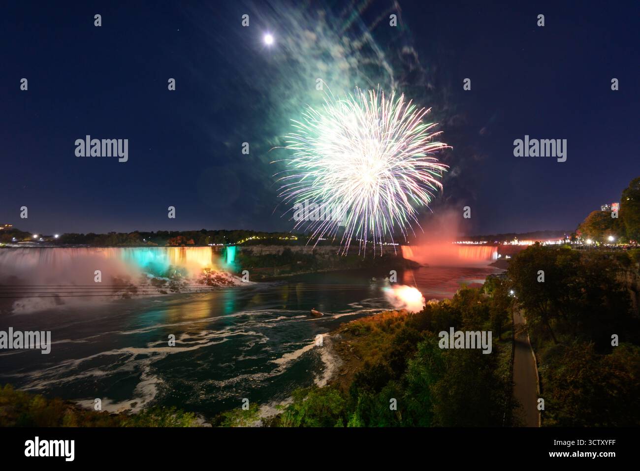 Una spettacolare vista notturna delle Cascate del Niagara, con le Canadian Horseshoe Falls e le American Falls illuminate da vibranti fuochi d'artificio. Foto Stock