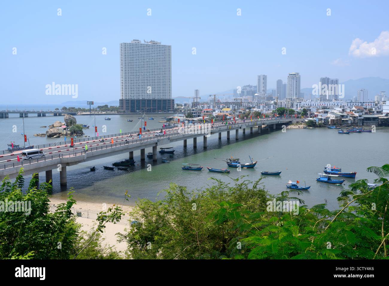 NHA TRANG, VIETNAM - 25 APRILE 2025. Vista della città con un ponte sul fiume Cai, grattacieli e barche da pesca Foto Stock
