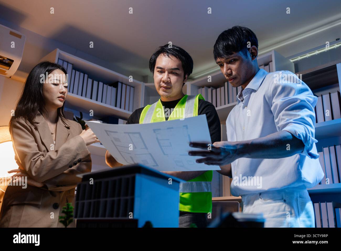 Un team diversificato di professionisti condivide idee su layout architettonici e concetti strutturali, concentrandosi sul lavoro di squadra, la creatività e la precisione in m Foto Stock