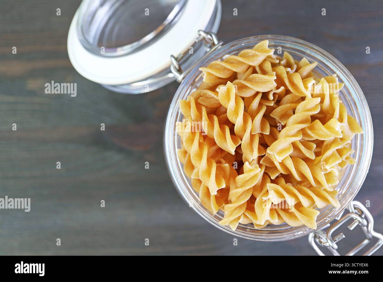 Fusilli di grano intero crudo e essiccato, conservati in un vaso di vetro Foto Stock