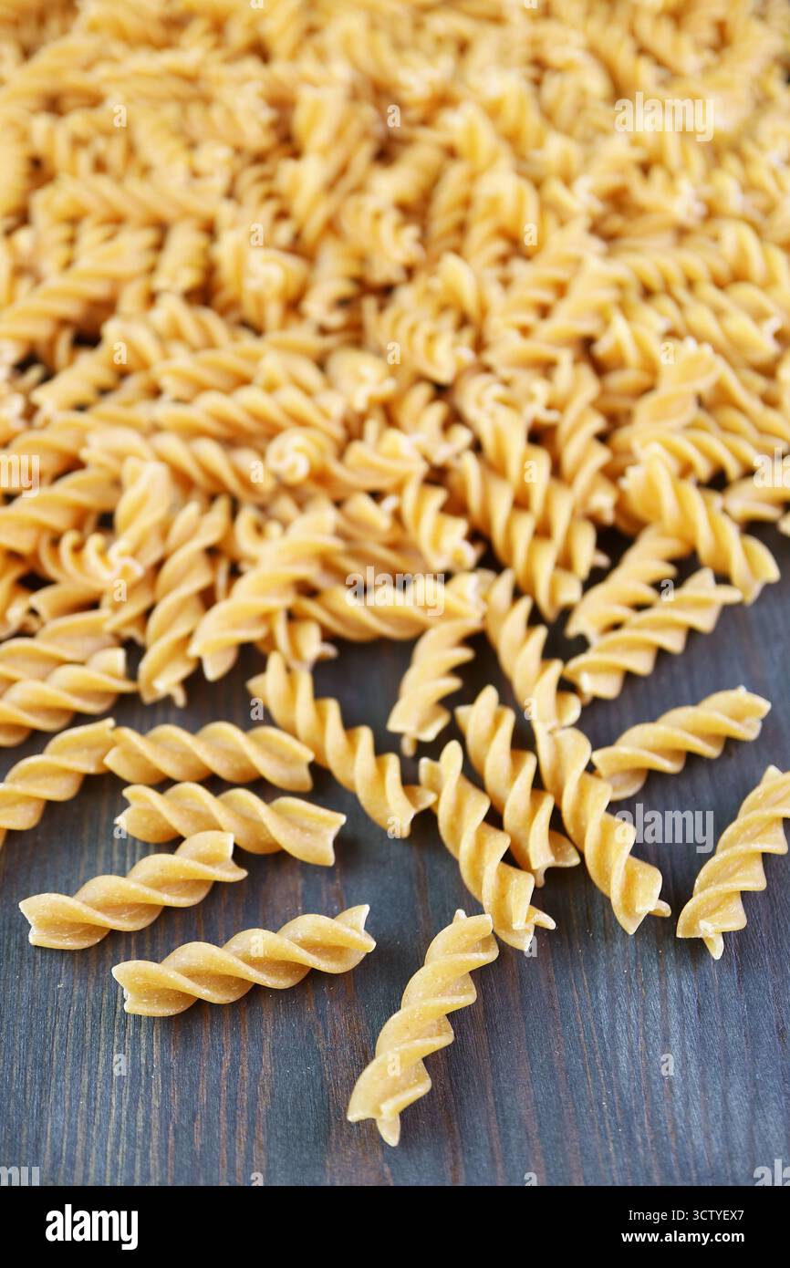 Mucchio di Fusilli di grano intero crudo sparsi su fondo in legno Foto Stock
