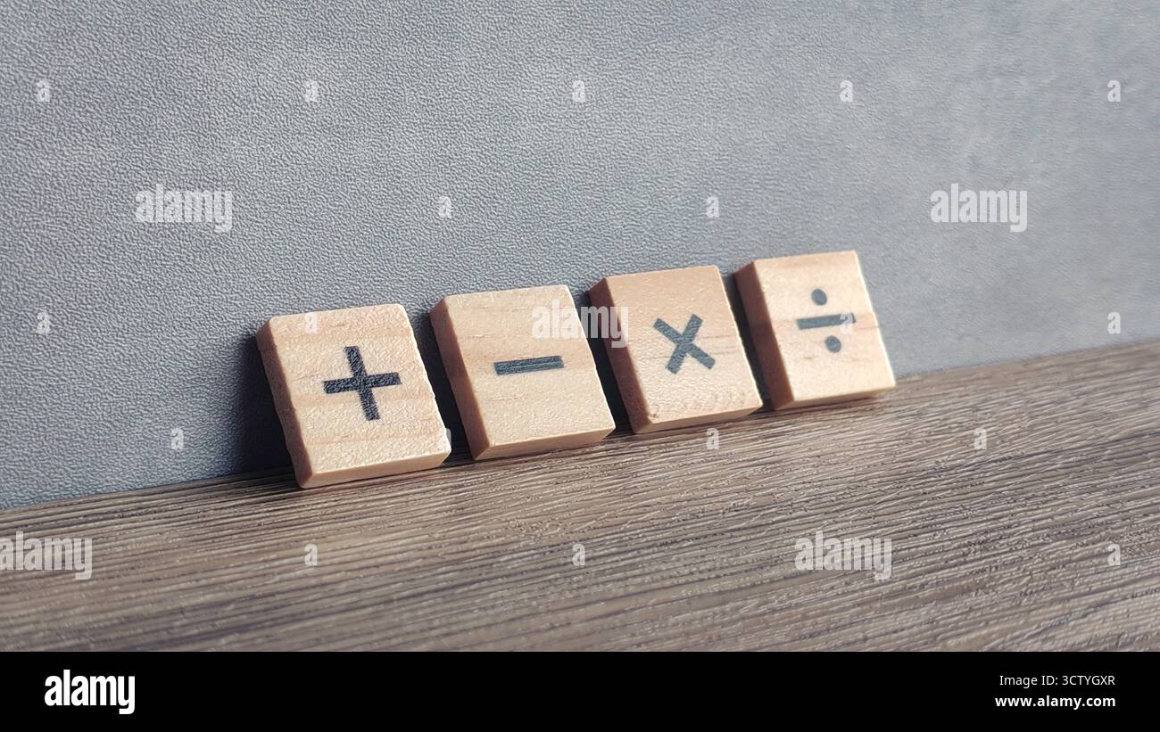 Quattro segnali fondamentali di operazioni matematiche su blocchi di legno: Addizione, sottrazione, moltiplicazione e divisione per l'istruzione e i concetti aziendali. Foto Stock