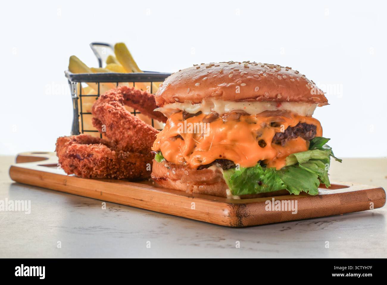 Doppio Patty di manzo macinato frantumato, salsa al parmigiano all'aglio, Cheddar a fette, anelli di cipolla, Rocket, e lattuga Burger Foto Stock