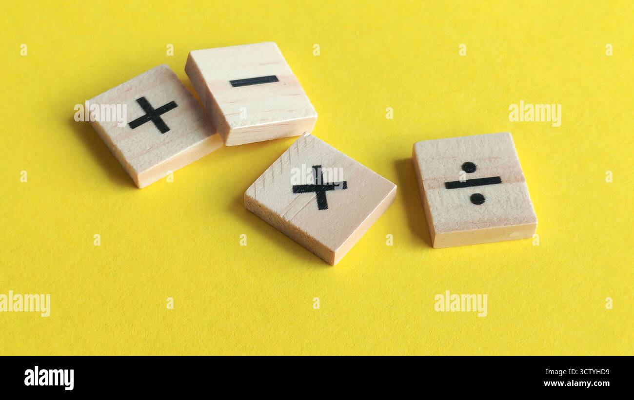 Blocchi di legno sparsi con simboli matematici fondamentali su uno sfondo giallo brillante, che rappresentano l'istruzione, la crescita e le decisioni finanziarie. Foto Stock
