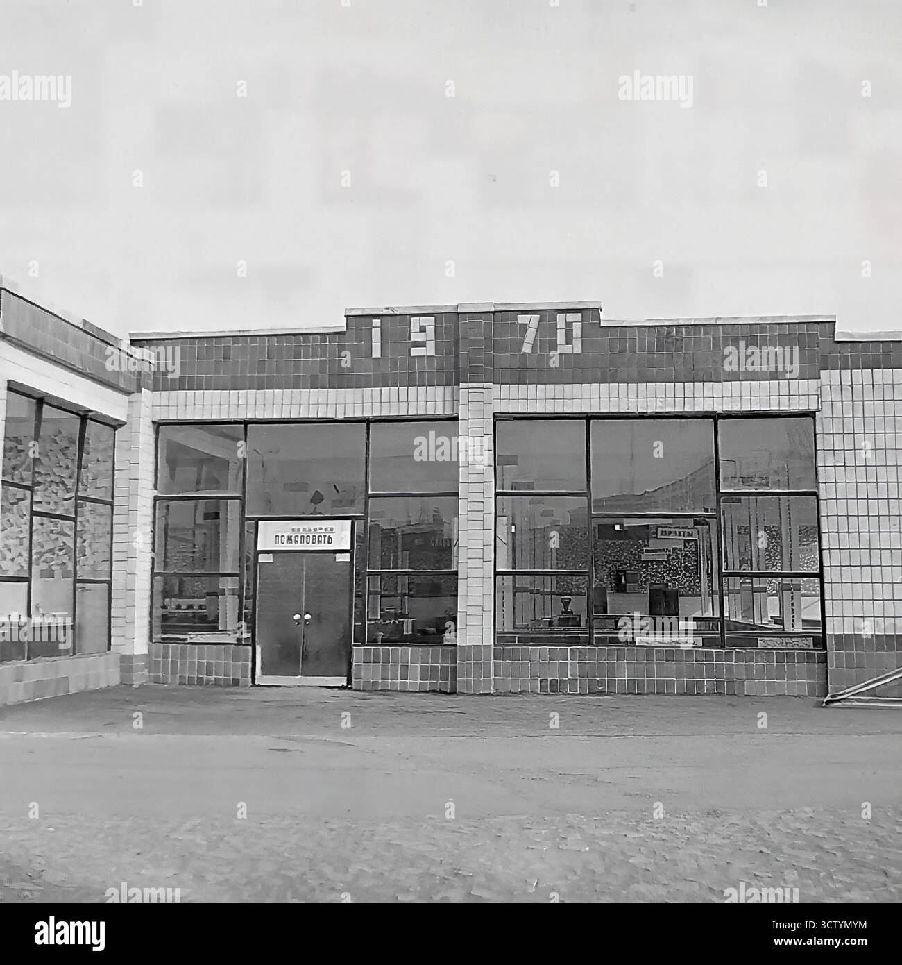 L'ingresso centrale di un nuovo mercato coperto a Sloviansk, la RSS Ucraina, è catturato in questa foto architettonica esplicitamente datata 1970 sulla sua facciata. Questo edificio e' un ottimo esempio di design modernista sovietico, caratterizzato da un esterno piastrellato, grandi finestre di vetro e un cartello 'Dobro Pozhalovat' (benvenuto) sulla porta. L'importante esposizione dell'anno segna il suo completamento durante il centenario della nascita di Lenin, rendendolo un artefatto significativo dello sviluppo urbano dell'era Brezhnev Foto Stock