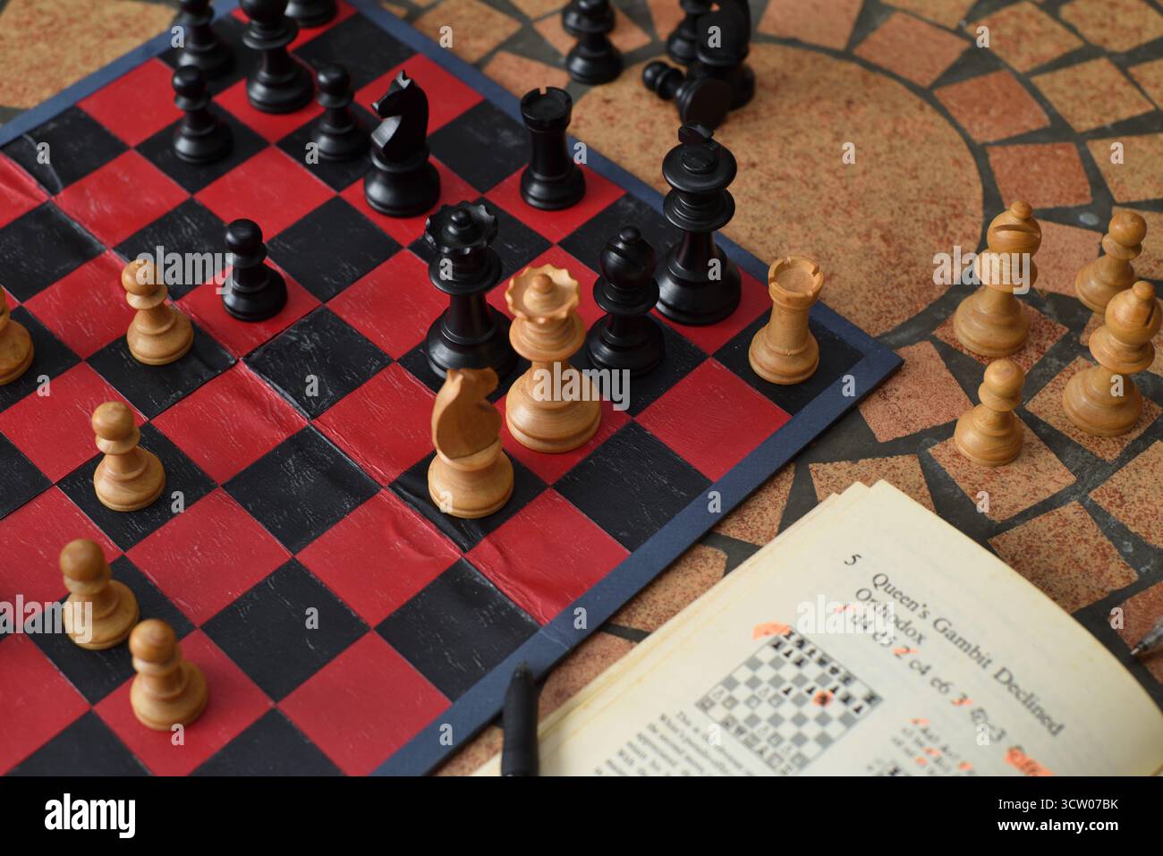 Compagno in uno? Imparando gli scacchi del gambetto della regina che aprono il re e la regina nell'angolo, gli scacchi Staunton del boxwood su una tavola rossa e nera Foto Stock