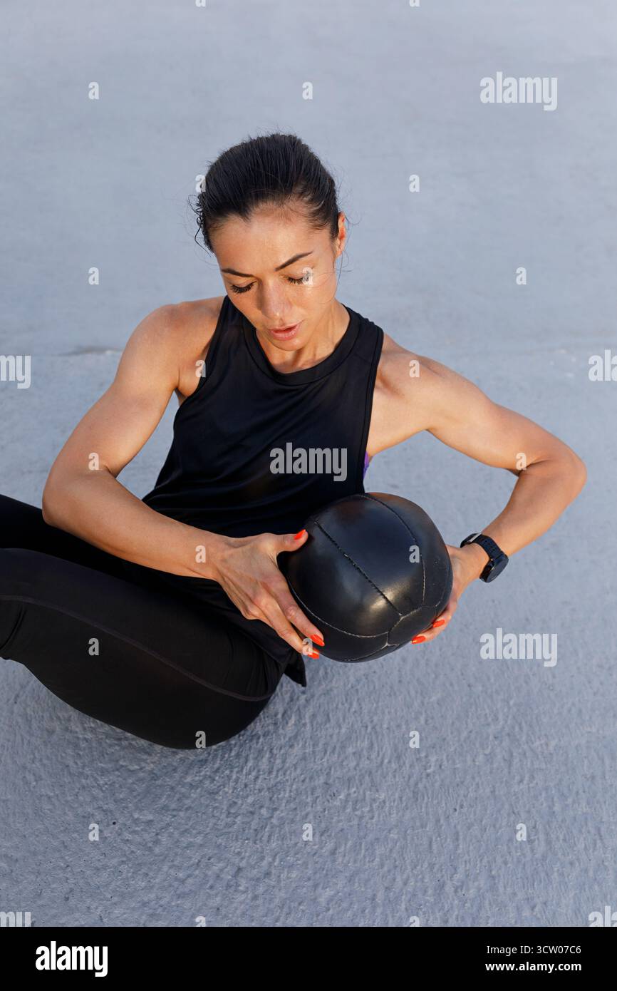 Vista ad alto angolo di una giovane atleta muscolosa che fa esercizi di base con una palla medica Foto Stock
