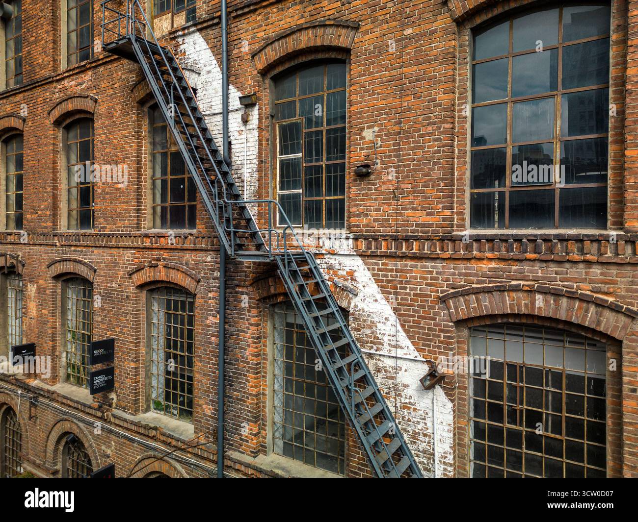 Facciata di edifici industriali in mattoni, scala di sicurezza antincendio in metallo ripido, architettura urbana, atmosfera ricoperta, orizzontale, dettagli testurizzati, foto drone, hist Foto Stock