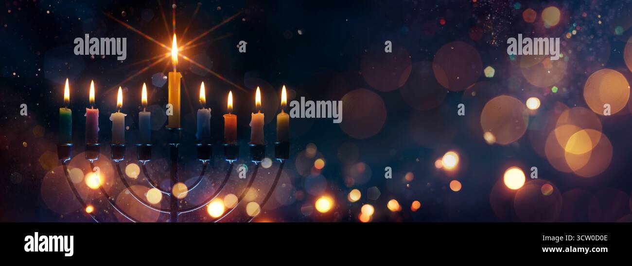 Hanukkah Menorah - candele accese al buio con luci sfocate astratte e scintillanti - chiave bassa Foto Stock
