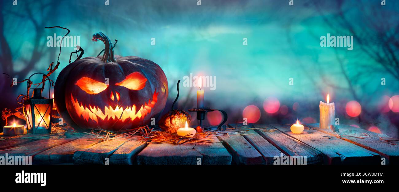Halloween Pumpkins on Table at Twilight - Jack o' Lantern in Defocused Forest Foto Stock