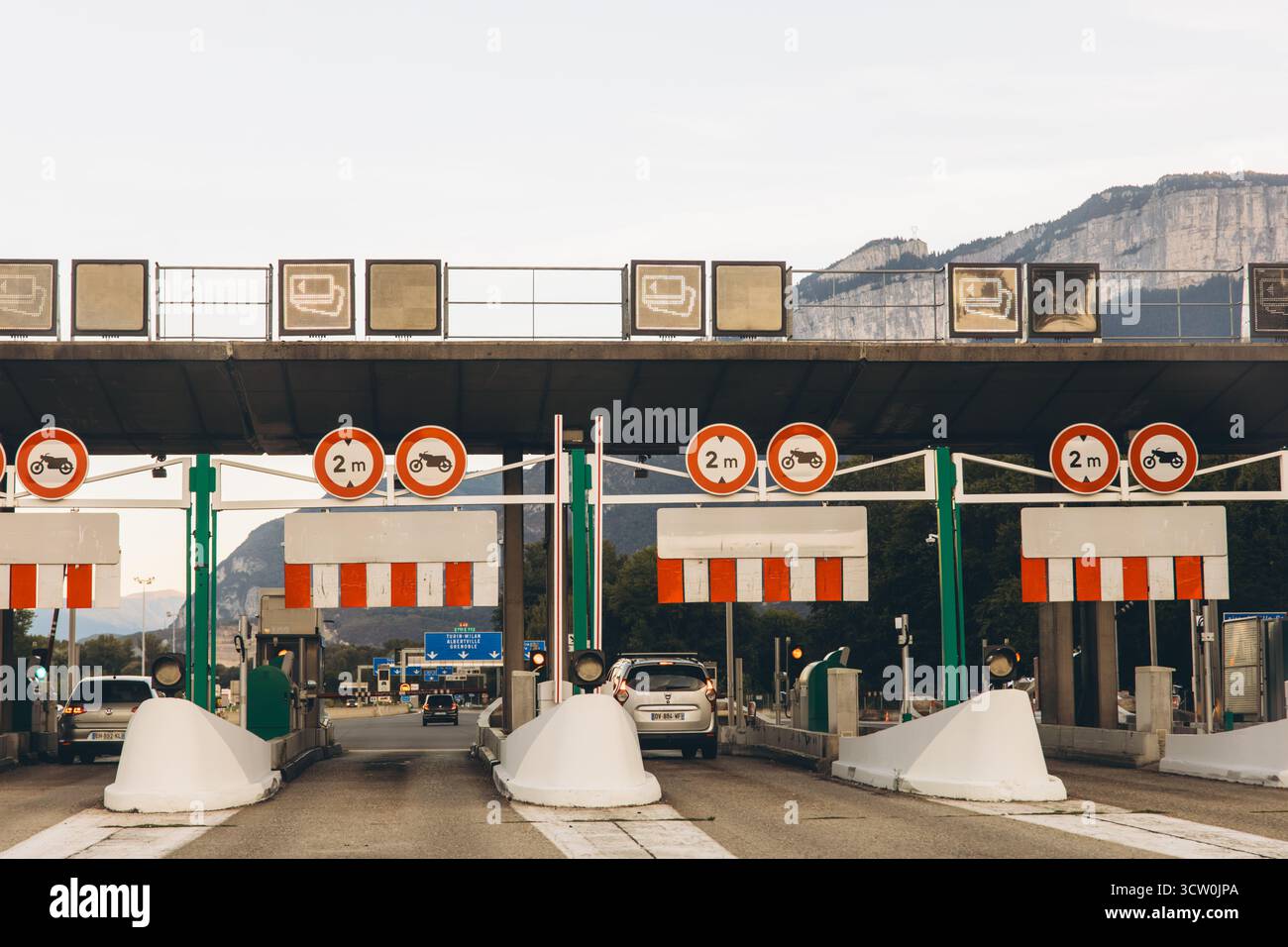 Italia, 6 settembre 2025, stazione a pedaggio su un'autostrada italiana con più corsie e veicoli di passaggio. Paesaggio di montagna sullo sfondo. Pagato Foto Stock