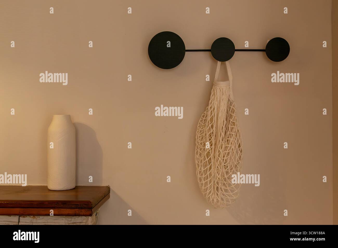 Interno minimalista con appendiabiti da parete e borsa in mesh riutilizzabile, arredi ecologici per la casa, spazio per le copie Foto Stock