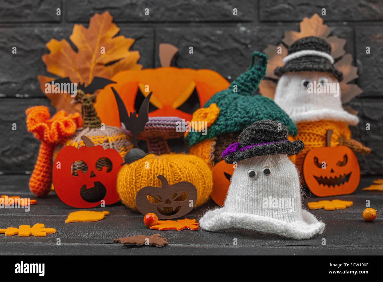 Accogliente scena di Halloween con graziose statuette di fantasmi in piccoli cappelli. Decorazioni autunnali lavorate a mano, zucche all'uncinetto, foglie autunnali, bacche, ragni, e gho Foto Stock