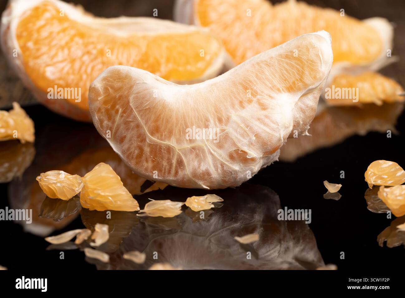 metà agrumi su una superficie nera a specchio, agrumi dolci e succosi si riflettono sulla superficie nera, primo piano Foto Stock