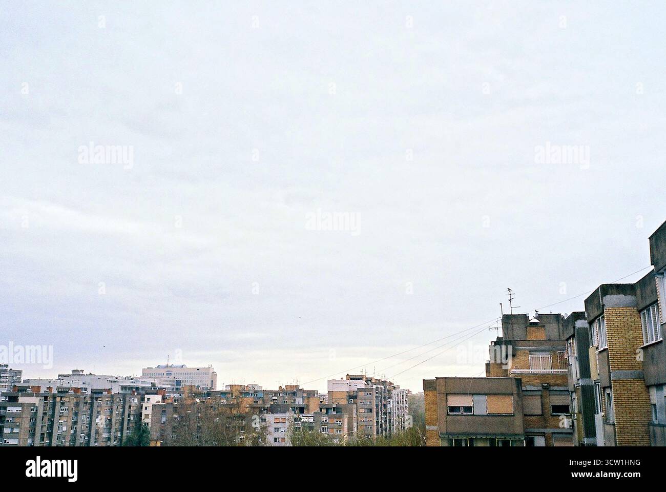 Foto d'archivio analogica di tetti brutalisti in mattoni gialli sotto il cielo coperto. Forte spazio negativo e composizione minima. Architettura documentaria. Foto Stock