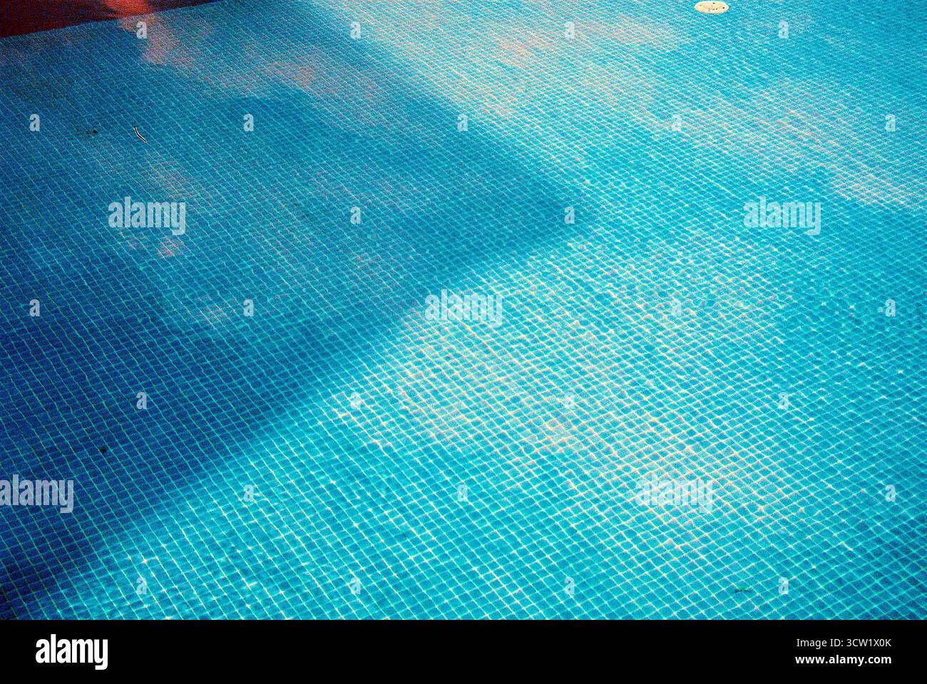 Foto analogica da 35 mm di un fondo blu turchese pulito con piastrelle a mosaico, luce solare e ombre morbide sulla superficie. Dettagli tranquilli e senza tempo. Foto Stock