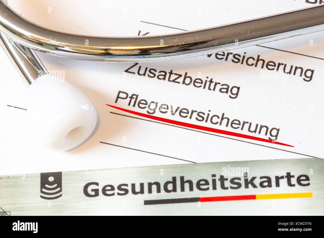 Primo piano della parola Krankenversicherung su un documento, accompagnato da una tessera di assicurazione sanitaria e uno stetoscopio Foto Stock