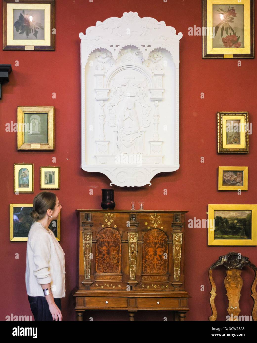 Londra, Regno Unito. 09 ottobre 2025. Personale con uno dei quattro "Ghost Objects" della collezione originale di Leighton, nel loro posto originale, ma accuratamente lavorato a mano in carta bianca - qui un ornamento. Leighton House segna 100 anni da quando l'ex casa dell'artista vittoriano Frederic Leighton aprì al pubblico come museo. Nell'ambito delle celebrazioni, vengono svelate anche le nuove opere di carta a grandezza naturale di Annemarieke Kloosterhof, ambientate su splendidi interni storici. Crediti: Imageplotter/Alamy Live News Foto Stock