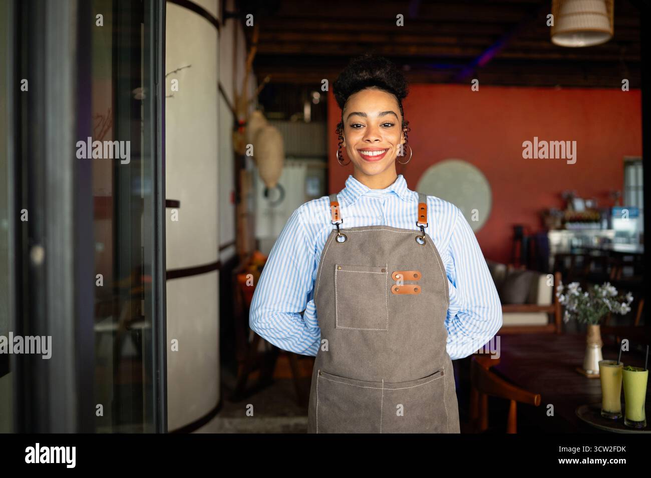 Orgoglioso proprietario di un caffè che si trova con fiducia dietro il bancone, pronto a servire i clienti con un sorriso caldo Foto Stock