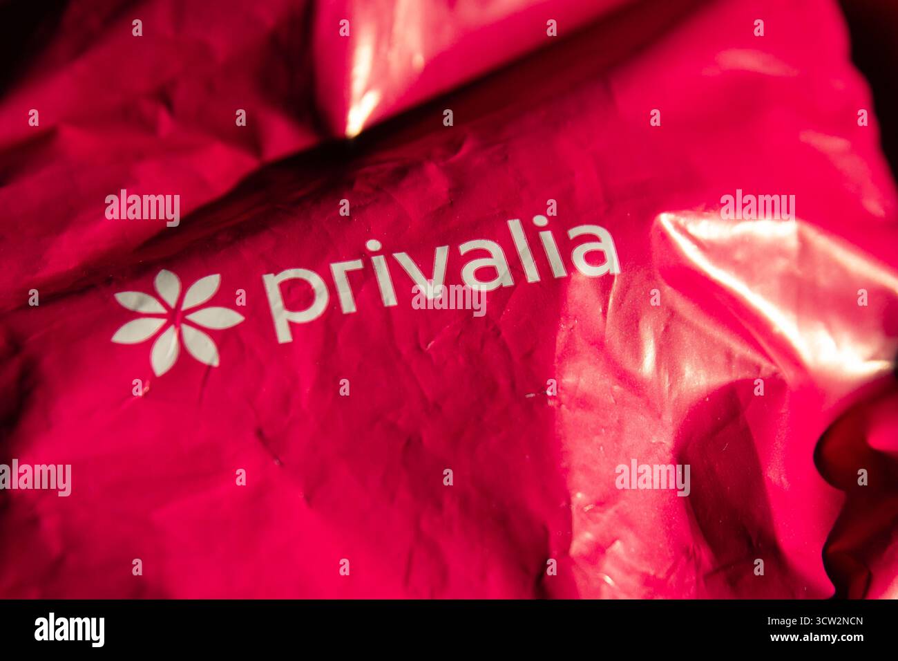 Una borsa da imballaggio Privalia rossa con l'emblema del fiore e il logo del marchio, che enfatizza un design audace ed eco-consapevole. Foto Stock