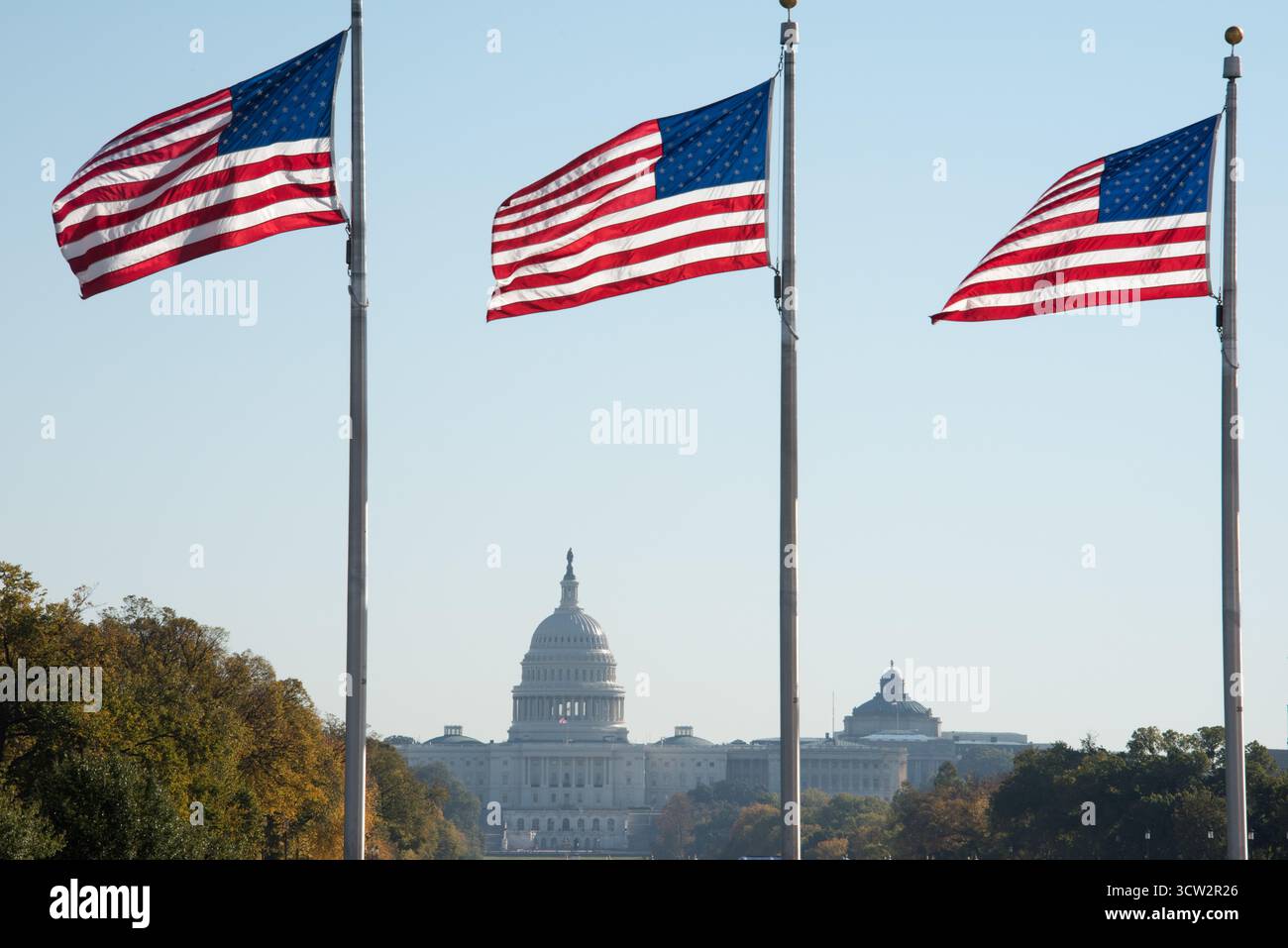Campidoglio degli Stati Uniti con American Flags Washington DC // WASHINGTON DC - tre bandiere americane volano in modo prominente con il Campidoglio degli Stati Uniti sullo sfondo. L'iconica cupola del Campidoglio degli Stati Uniti è il luogo d'incontro del Congresso degli Stati Uniti, il ramo legislativo del governo federale. Questa struttura è un potente simbolo della democrazia e della governance americana, situata su Capitol Hill all'estremità orientale del National Mall. La sua architettura neoclassica e la caratteristica cupola sono riconosciute in tutto il mondo. Foto Stock