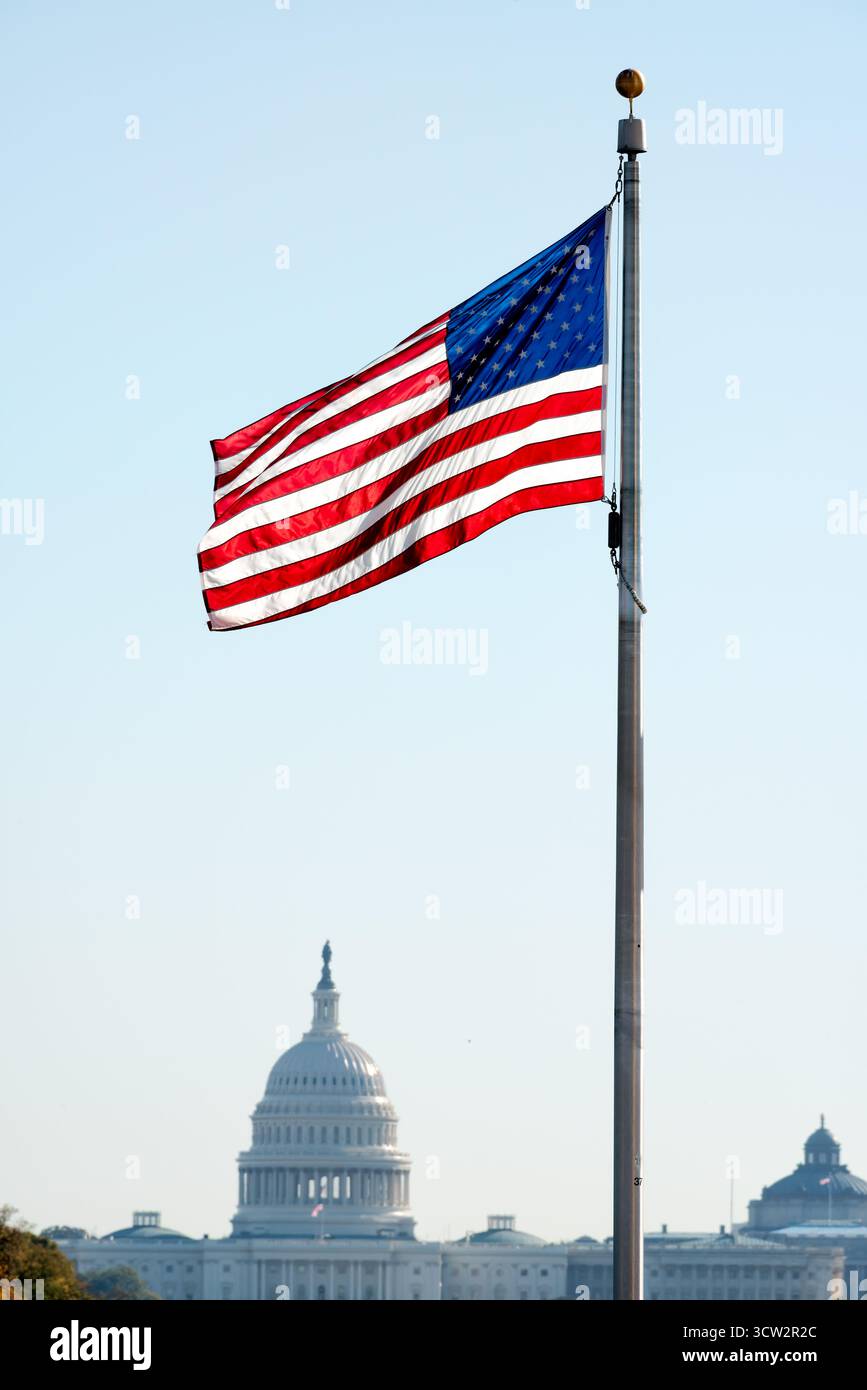 American Flag on Flagpole Washington DC // WASHINGTON DC - una bandiera americana vola in modo prominente su un palo, un potente simbolo nazionale degli Stati Uniti. Sullo sfondo, è visibile l'iconica cupola del Campidoglio degli Stati Uniti. Il Campidoglio è il luogo d'incontro del Congresso degli Stati Uniti, il ramo legislativo del governo federale. Situato su Capitol Hill, è un punto di riferimento significativo a Washington DC, che rappresenta la democrazia e il governo americani. Foto Stock