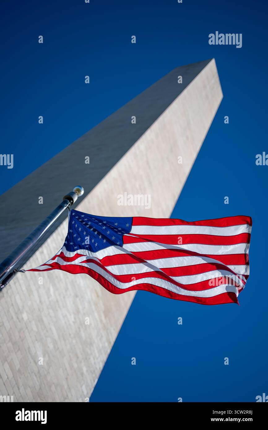 Washington Monument e American Flag Washington DC // WASHINGTON DC - la bandiera americana vola in modo prominente con il Washington Monument sullo sfondo, un iconico obelisco in onore di George Washington, il primo presidente degli Stati Uniti. Questo monumento nazionale si trova sul National Mall di Washington D.C. ed è gestito dal National Park Service. Costruito in marmo, granito e gneiss di pietra blu, il monumento è alto 169,046 metri (554 piedi 7 pollici). Completato nel 1884, è un potente simbolo della storia americana e dell'unità nazionale. Foto Stock Washington Monument e American Flag Washington DC // WASHINGTON DC - la bandiera americana vola in modo prominente con il Washington Monument sullo sfondo, un iconico obelisco in onore di George Washington, il primo presidente degli Stati Uniti. Questo monumento nazionale si trova sul National Mall di Washington D.C. ed è gestito dal National Park Service. Costruito in marmo, granito e gneiss di pietra blu, il monumento è alto 169,046 metri (554 piedi 7 pollici). Completato nel 1884, è un potente simbolo della storia americana e dell'unità nazionale. Foto Stock
