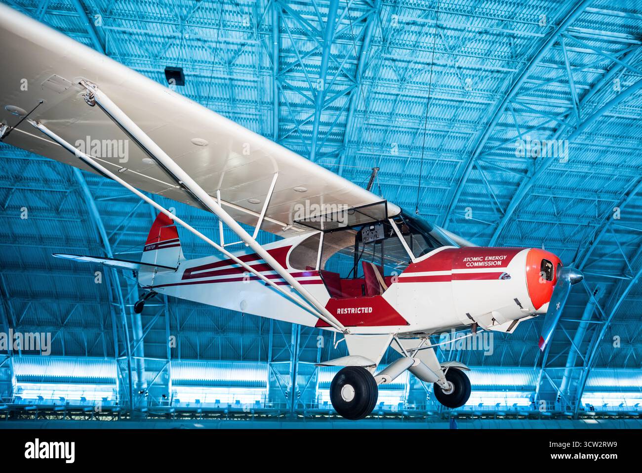 Piper PA-18 Super Cub Atomic Energy Commission Chantilly Virginia // CHANTILLY, Virginia, Stati Uniti — Un Piper PA-18 Super Cub, dipinto di rosso e crema con la "Atomic Energy Commission" sulla fusoliera, è esposto allo Steven F. Udvar-Hazy Center. Questo monoplano ad ala alta dell'aviazione generale del 1946 fu utilizzato dall'AEC negli anni '1950 per l'esplorazione dell'uranio nell'ovest americano, scelto per le sue capacità di volo basso e lento su terreni accidentati. Dotato di un contatore di scintillazione nella parte posteriore per rilevare le radiazioni gamma, l'aereo fa parte della mostra dell'aviazione della seconda guerra mondiale. La P Foto Stock